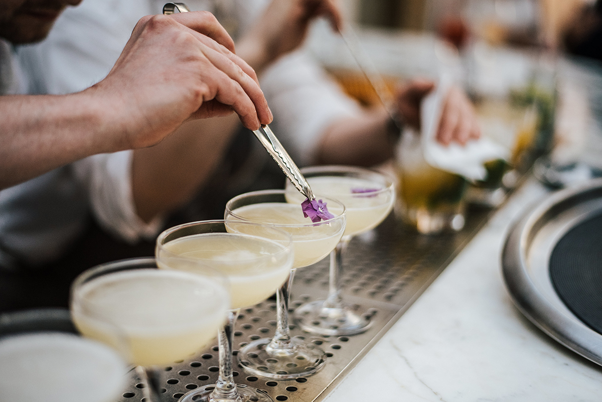 Closeup shot of a barman making margaritas with five glasses set in line